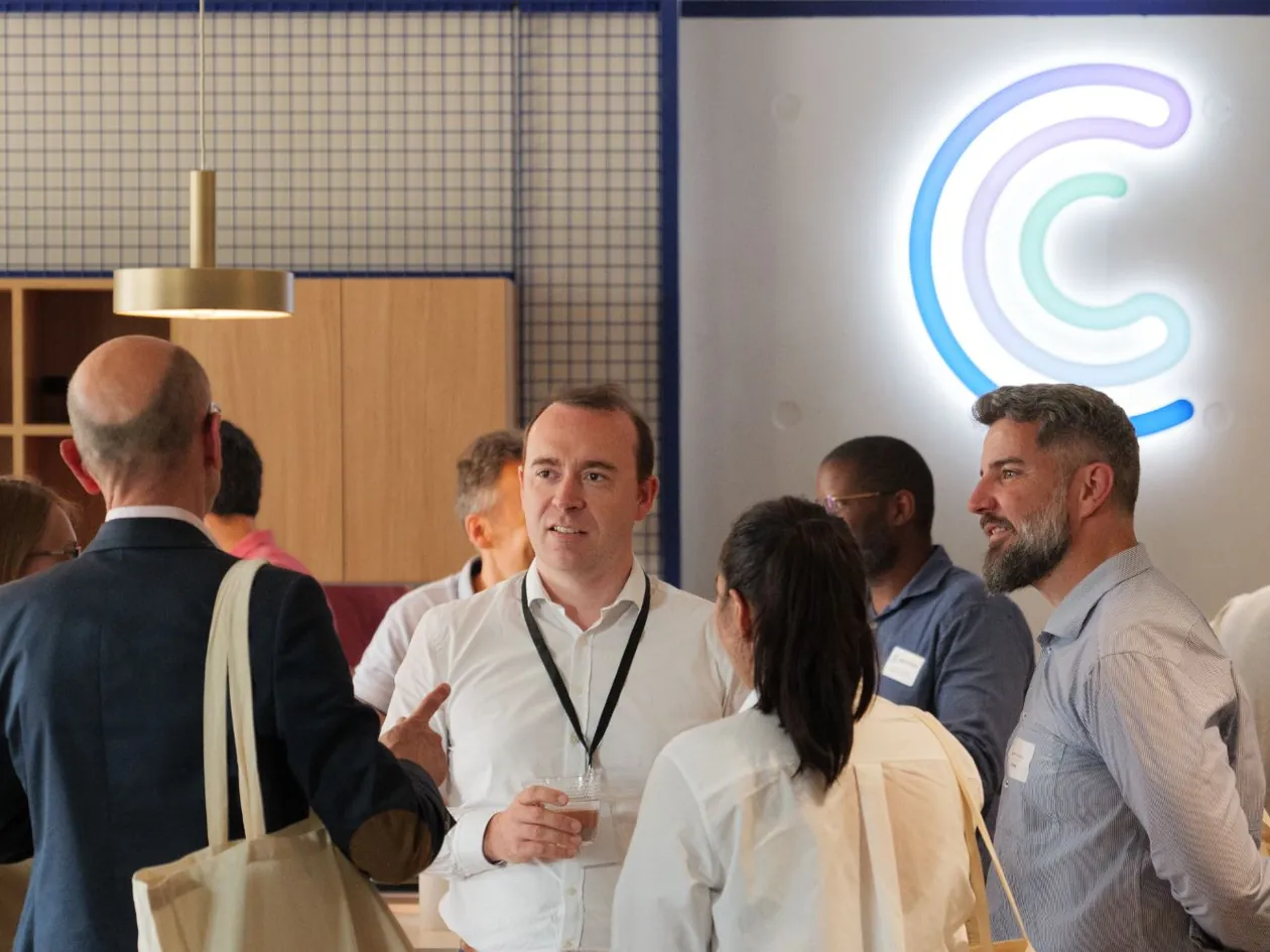 Der CEO von Centreon im Gespräch mit Gästen bei einer Veranstaltung in den Centreon-Büros, unter dem beleuchteten Logo
